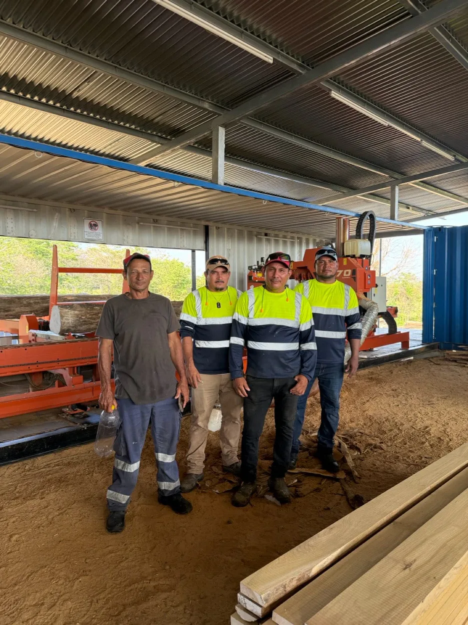 The milling team standing in front of the sawmill equipment